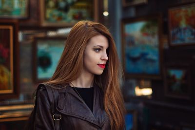 Close-up of beautiful young woman standing against picture frames