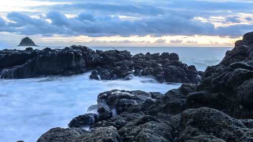 Scenic view of rocks in sea against sky during sunset