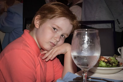 Portrait of boy by food and drink on table at restaurant