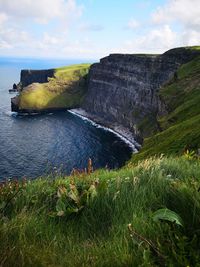 Scenic view of cliff by sea against sky