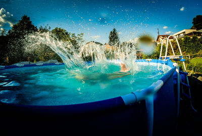 Man swimming in pool against blue sky