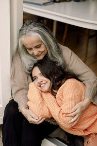 Senior woman embracing happy granddaughter while sitting at doorway