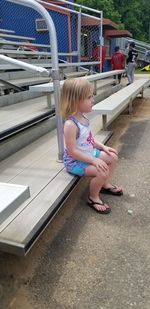 Full length of woman looking at camera while sitting in park