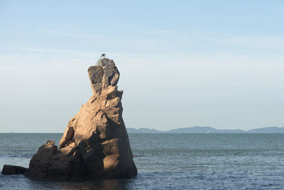 Rock formation on beach against sky