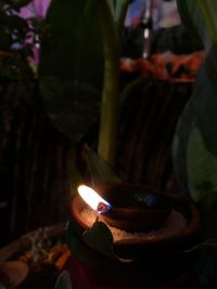 Close-up of hand holding illuminated candle