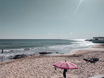 Scenic view of beach and an umbrella against clear sky