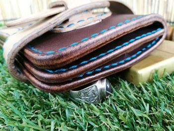 Close-up of leather wallet and ring on grass at park