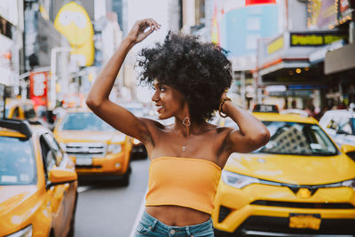 Fashionable young woman with afro hairstyle standing on city street