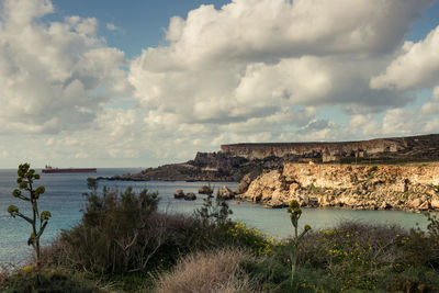 Scenic view of sea and mountains against cloudy sky