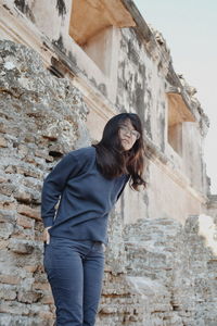 Portrait of woman standing against brick wall