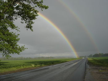 Rainbow over road against sky