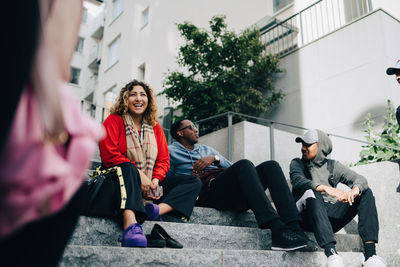 Full length of friends sitting in city