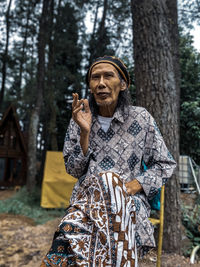 Mid adult man standing by tree trunk in forest