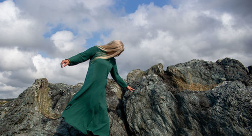 Low angle view of woman standing on rock against sky