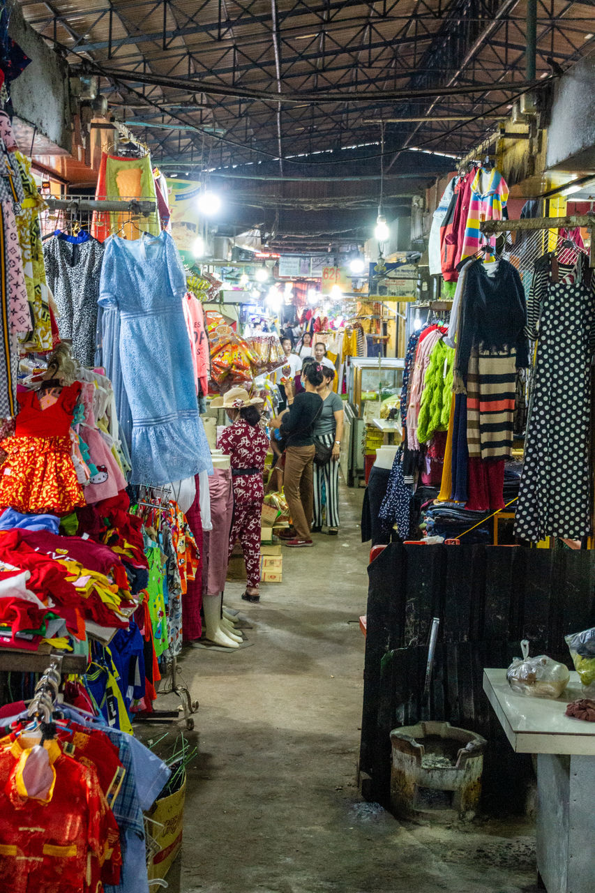 market, retail, choice, market stall, for sale, variation, small business, business, real people, abundance, shopping, large group of objects, hanging, incidental people, women, street market, buying, store, illuminated, multi colored, sale, consumerism, retail display