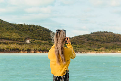 Rear view of young woman photographing sea