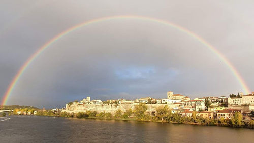 Rainbow over buildings in city against sky