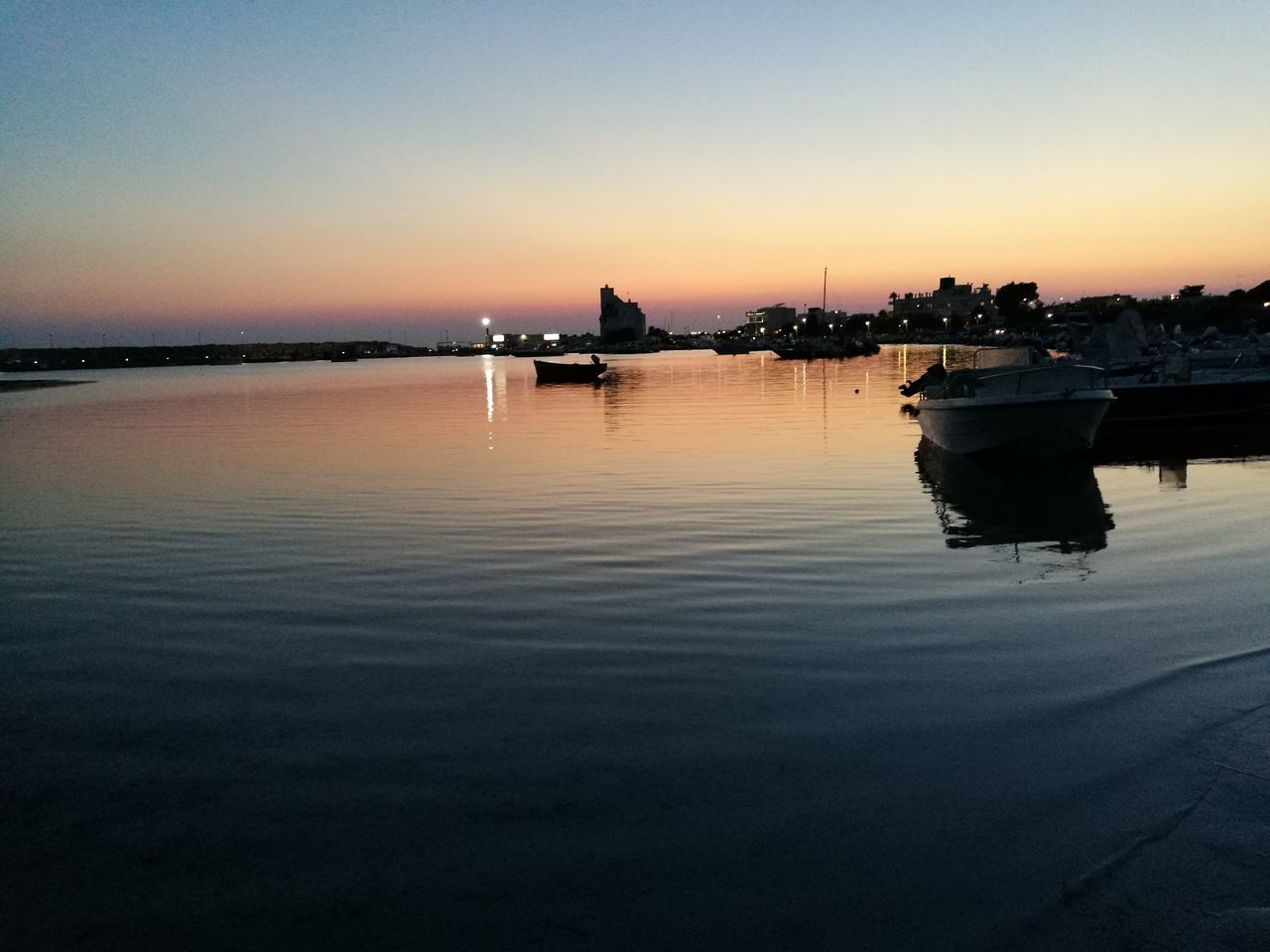 sunset, reflection, water, orange color, silhouette, beauty in nature, scenics, nature, sky, tranquility, tranquil scene, outdoors, transportation, nautical vessel, mode of transport, no people, architecture, built structure, sea, building exterior, clear sky, moored, day