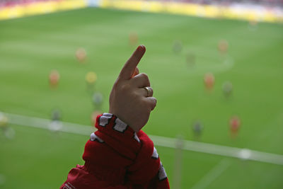 Cropped image of hand pointing against stadium