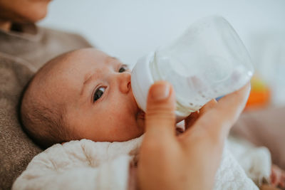 Close-up of mother feeding baby boy while sitting at home