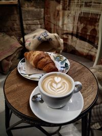 Cup of coffee on table. cappuccino and croissant. vintage italian bar in venice