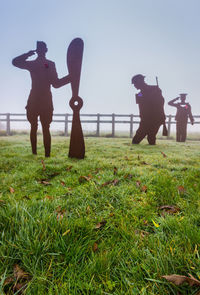 Silhouette people standing on field against clear sky