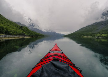 Boat on lake by mountains against cloudy sky