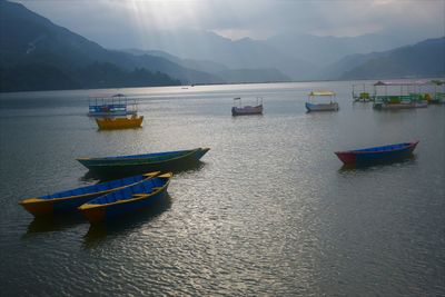 Fishing boats in sea against mountains