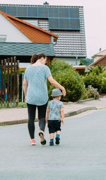 A little boy in a hat and shorts walks with his mother on the street on a fine summer day