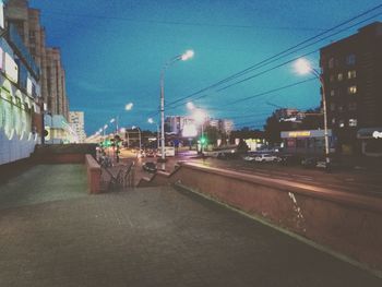 Illuminated city street against sky at night