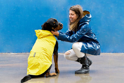 Happy woman with dog sitting against wall