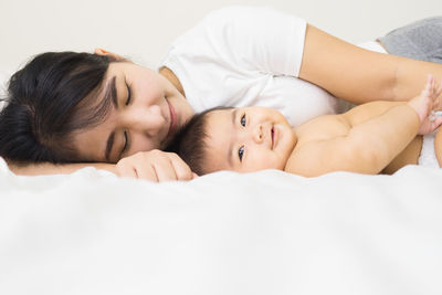 Close-up of happy mother and daughter on bed at home