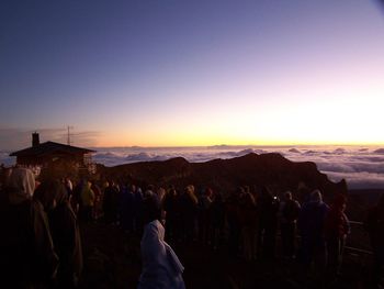 People standing on landscape against sky during sunset