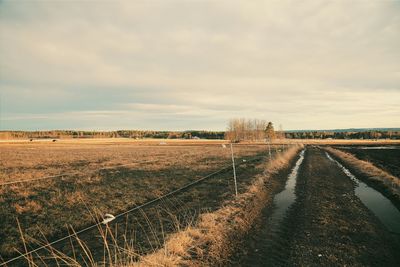 Scenic view of field against cloudy sky