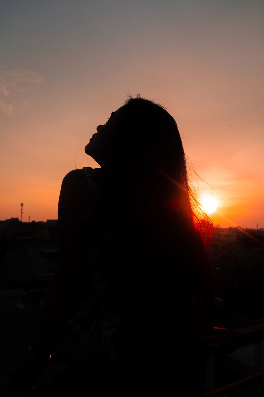 SILHOUETTE WOMAN STANDING AGAINST ORANGE SUNSET SKY