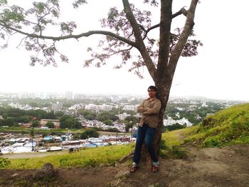 Portrait of man standing by tree against sky