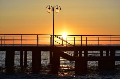 Bridge over sea against sky during sunset