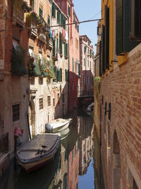 Boats moored in canal amidst buildings in city