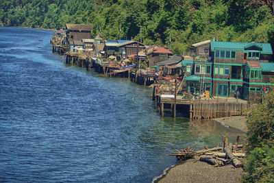 Houses by river against buildings