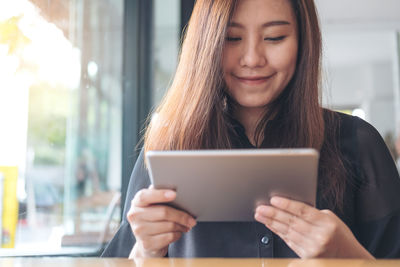 Smiling woman using digital tablet on table in cafe