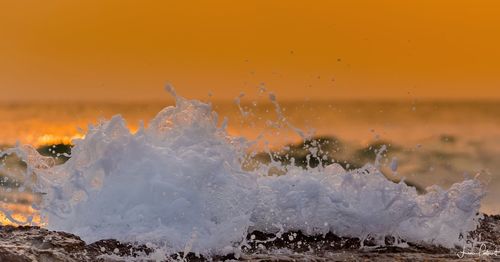 Close-up of sea waves splashing on shore during sunset