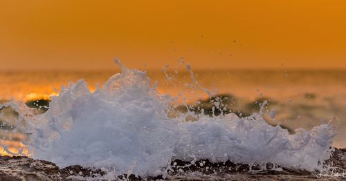Close-up of sea waves splashing on shore during sunrise. 