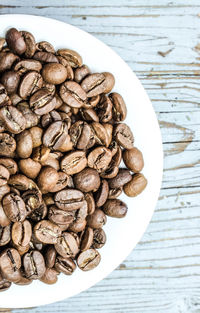 High angle view of roasted coffee beans in plate on table