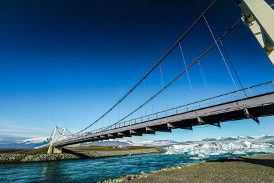 Low angle view of suspension bridge against blue sky