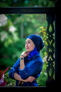 Portrait of young woman sitting on railing