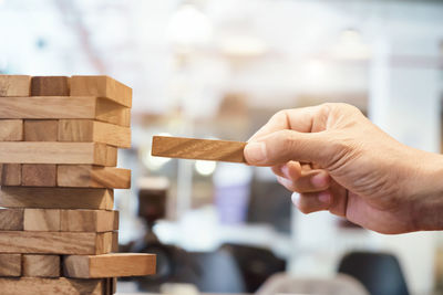 Cropped hand of man making wooden block stack