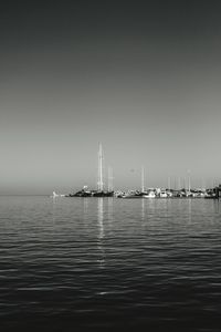 Sailboats in calm sea against clear sky