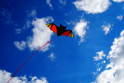 Low angle view of creative kite flying in blue sky