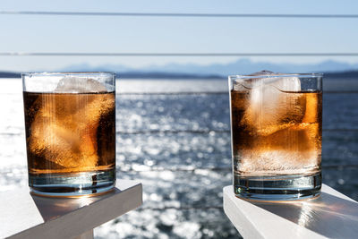 Close-up of glasses of whiskey against water