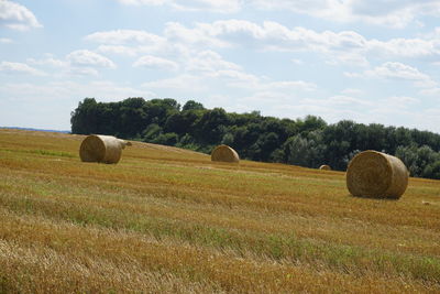 Hay bales on field against sky